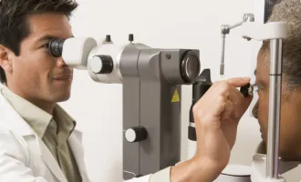 An eye doctor performing an eye exam on a patient using a slit lamp.